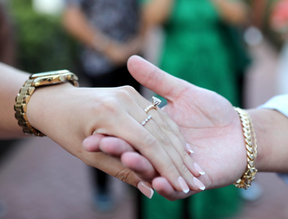 A couple's hands clasped together, displaying their wedding rings